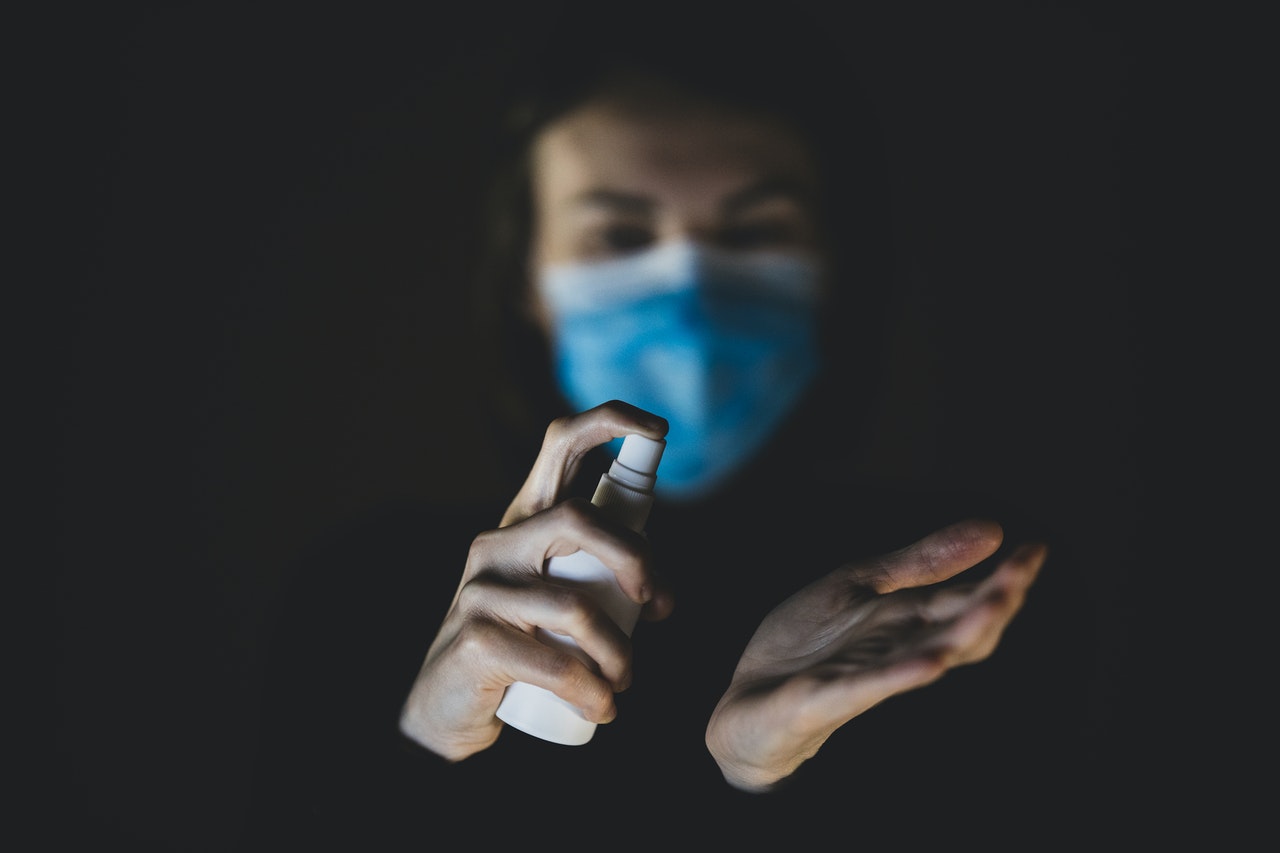 person with mask sanitizing